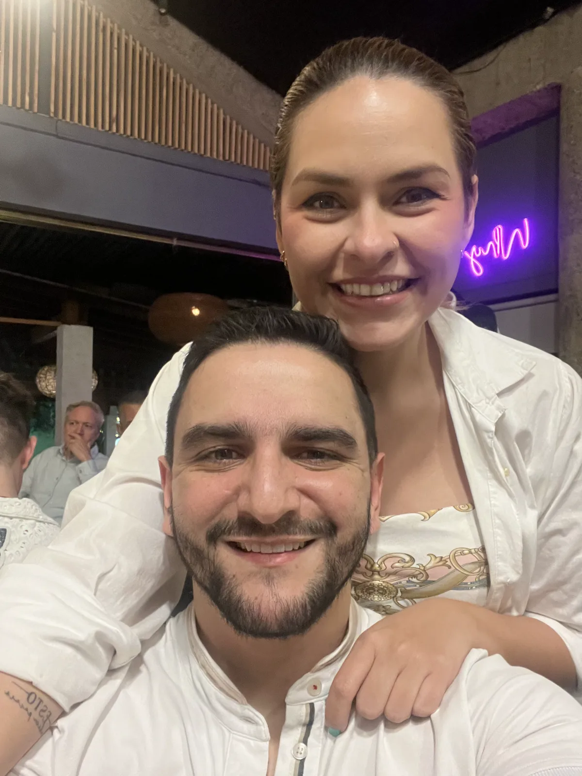 María Camila abraza a Juan Camilo por los hombros en una selfi en un restaurante